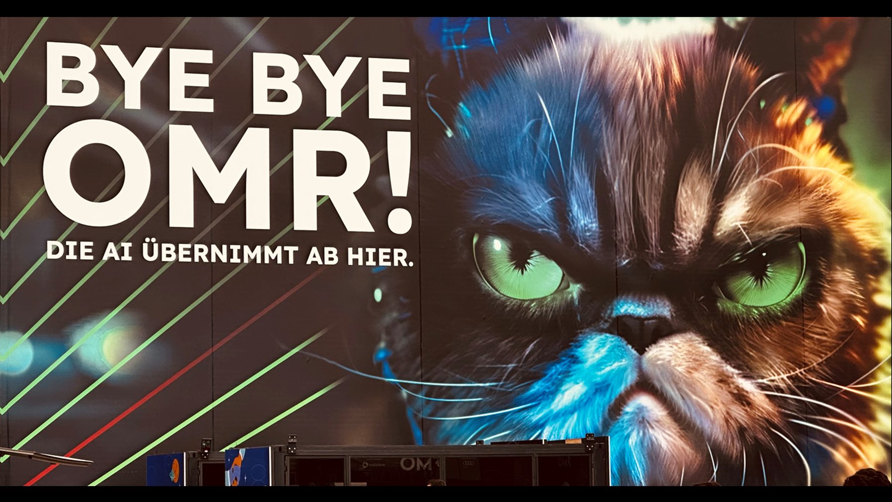 Foto zeigt eine Wand, auf der ein großer Katzenkopf zu sehen ist. Links neben dem Katzenkopf steht in großer, fetter Schrift „Bye Bye OMR! Die AI übernimmt ab hier.“